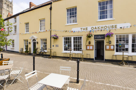 The Oakhouse Axbridge, Somerset. A Yellow Building With Bunting And Outside Seating.