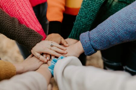 Colourful Jumpers And Hands Meeting In The Middle, Marketing For Small Business Requires Teamwork